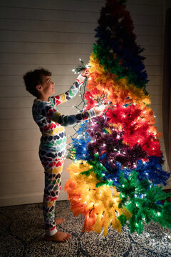 Girl in heart pjs adds lights to Christmas tree