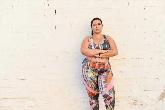 Sporty plus size woman leaning against a wall