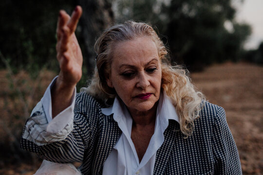 Portrait of senior woman siiting on the ground at olive grove with flamenco attitude.