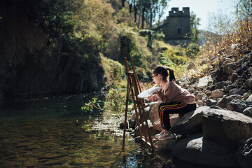 kid drawing beside river