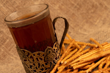 Salted breadsticks and salted pretzels in bulk and a glass of tea in a cup holder on the table.