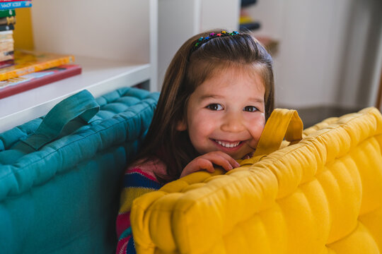 Playful Little Girl Hiding Behind Pillow