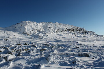Fototapeta na wymiar a rocky cliff on top of a snow-capped mountain