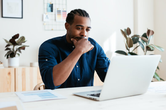Thoughtful black freelancer using laptop