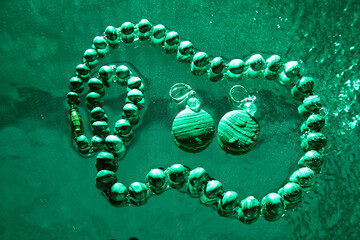 Jewelry from green malachite. Malachite beads in the studio on a glass surface with water