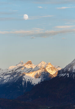 a bright moon in the sky above the mountains covered with snow
