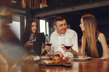 Friends talking and having fun at dinner party. Elegantly dressed group of people having a dinner.
