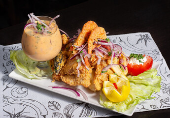 Peruvian traditional food. Fried fish with shrimp, onion, lemon, tomatoes and sauce. Chicharron de pescado