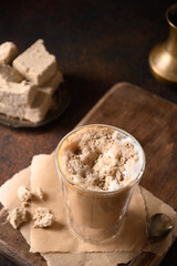 Tasty coffee latte with halva in glass cup.