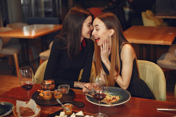 Friends talking and having fun at dinner party. Elegantly dressed women of people having a dinner.