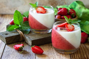 Panna cotta with strawberry jelly and fresh strawberries on a rustic wooden table, summer italian...