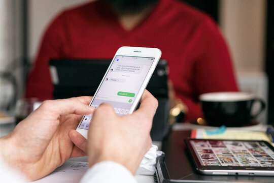 Business: Man Checks Text Message During Meeting With Team