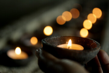 Person holding candle light in the dark on candles bokeh lights background. Love hope and peace...