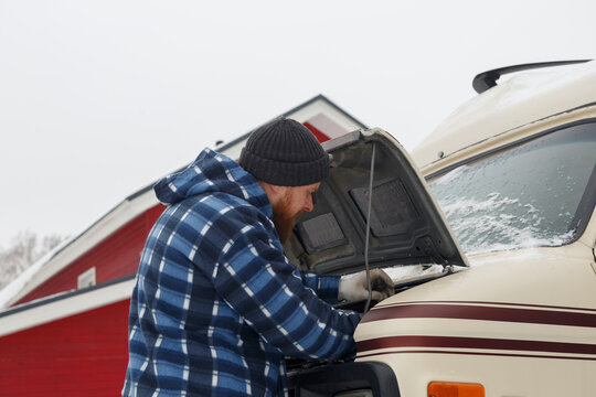 Bearded guy fixing van on cold day
