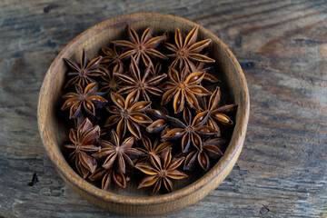 Anise star. Stars in a wooden plate on a brown background. Fragrant seasoning. The bowl is on the rustic table