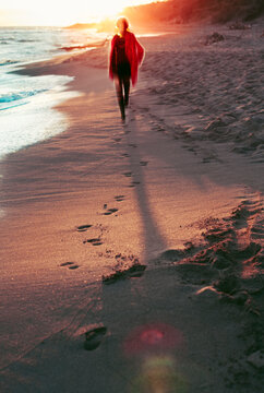 Anonym woman in red coat on the beach