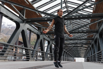 Sportsman exercising with jumping rope on bridge