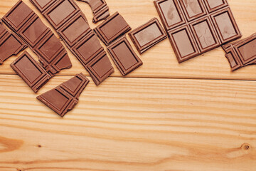 broken bar of chocolate on wooden background texture sweets