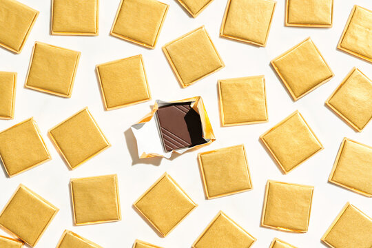 Unwrapped chocolate near pieces in golden wrappings