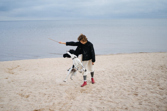 Woman playing with dog on the seashore