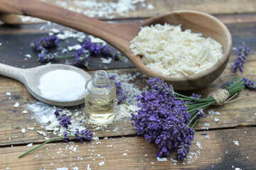Obraz na płótnie Canvas spoon full of flakes of soap with essential oil and bunch of lavender with bicarbonate on wooden background