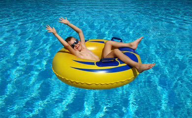 Boy relaxing on the inflatable ring in swimming pool.