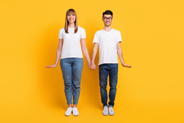 Full length photo of charming funny couple wear white t-shirt spectacles smiling hands arms sides isolated yellow color background