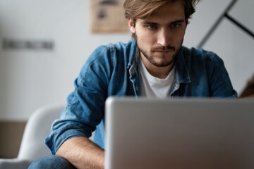 Successful entrepreneur smiling in satisfaction as he checks information on his laptop computer while working