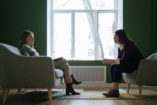 two women sit opposite each other during a psychotherapy session