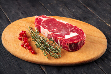 Side view on raw piece of meat with rosemary on the wooden board
