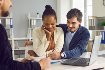 Happy interracial young family couple signing papers after consultation with personal financial advisor about health insurance, budget planning, loan mortgage agreement, real estate sale purchase deal