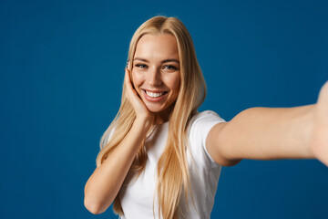 Fototapeta premium Blonde young happy woman smiling while taking selfie photo