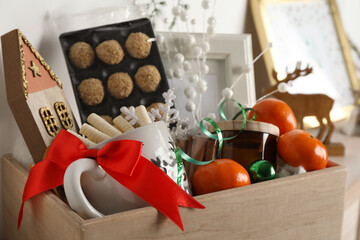 Crate with gift set and Christmas decor on shelf, closeup