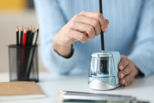 Female hands sharping pencil with electronic sharpener closeup