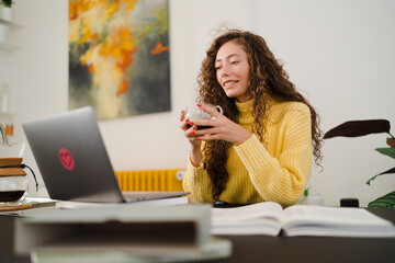 Young student with hot drink doing homework