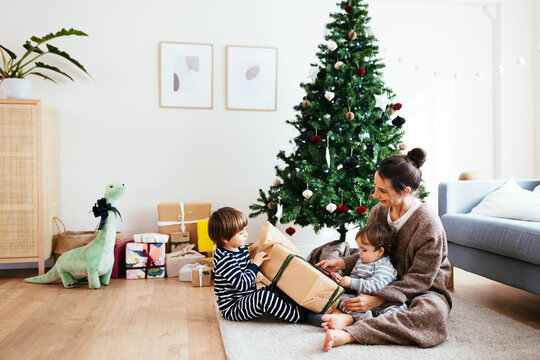 Mother And Children Unwrapping Christmas Present