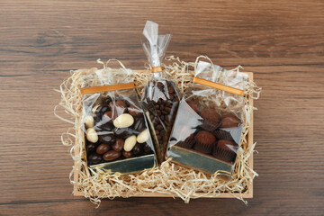Gift box with chocolate candies and coffee beans on wooden table, top view