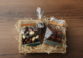 Gift box with chocolate candies and coffee beans on wooden table, top view