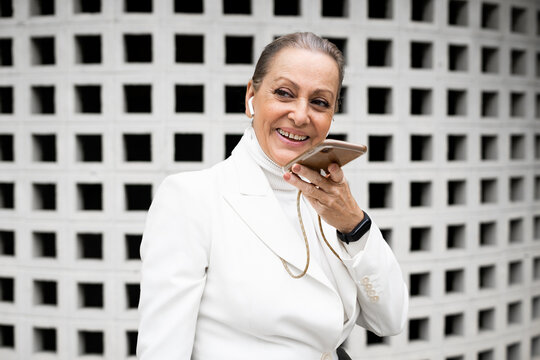 senior business woman at street talking by phone and smiling