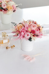 Bouquet with roses, peonies and hydrangea in pink colors. Stabilized flowers in a white ceramic vase at home on the dressing table. Interior decor.