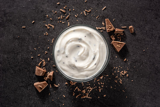 Stracciatella yogurt in transparent bowl on black background. Top view