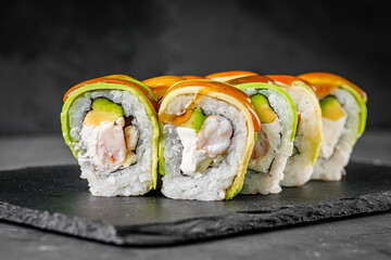 appetizing green dragon sushi roll with philadelphia cucumber shrimp and avocado on a black stone plate