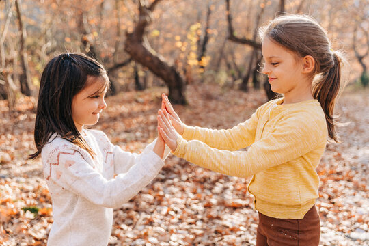 Playful girls in autumn forest full with dry leafs