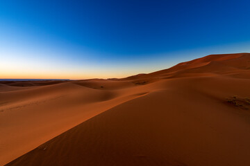 Fototapeta na wymiar Scenic view of the beautiful Erg Chebbi dunes at dawn, with a camel caravan on the background, in Morocco, North Africa