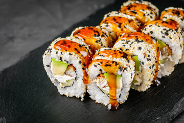 appetizing sushi roll california with eel avocado cucumber and sesame seeds on a black stone plate