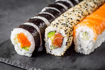 appetizing set of sushi roll on a black stone plate