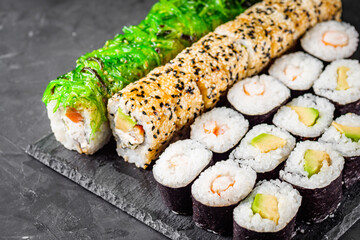 appetizing set of sushi roll on a black stone plate