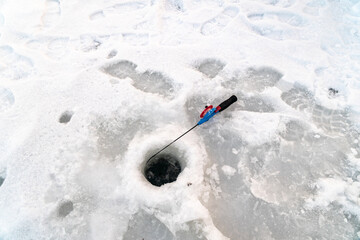Ice Fishing pole next to ice hole