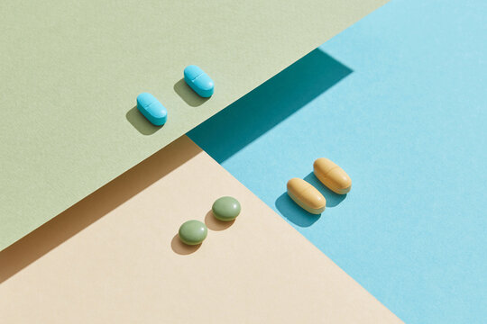 Medical pills on a paper geometric background.