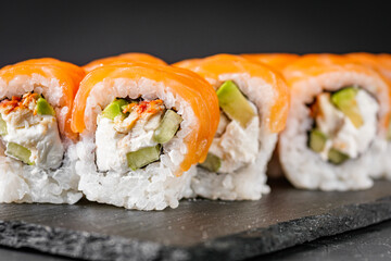 appetizing sushi roll philadelphia with avocado cheese eel cucumber and salmon on a black stone plate